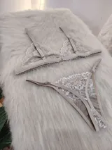 Conjunto de lencería compuesto por un bralette triangular de encaje con breteles regulables y una tanga a juego con laterales ajustables.