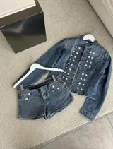 Chaqueta de denim azul con diseño de inspiración militar napoleónica, cuello mao, mangas largas y doble botonadura frontal con botones metálicos plateados en relieve.
