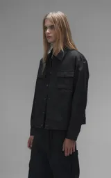 Chaqueta de corte regular crop confeccionada en microfibra pesada levemente elastizada. Presenta un diseño inspirado en la campera de jean clásica, con cuello volcado, cierre frontal mediante broches snap a tono y dos bolsillos delanteros con solapa.