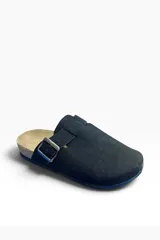 Zueco de gamuza color tostado, con diseño cerrado en la parte delantera y tira ajustable con hebilla metálica en el empeine. Cuenta con suela de corcho y base de goma antideslizante.