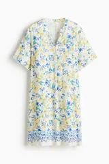 Vestido túnica corto a la rodilla de viscosa color blanco, con diseño estampado de limones y detalles florales en tonos amarillos y azules, escote en V con cuello mao y mangas cortas.