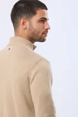 Buzo tejido liso de algodón color beige, con cuello alto, cierre frontal parcial y detalle de tirador en cuero.