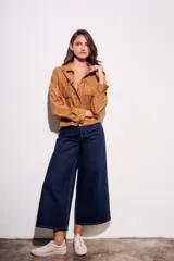 Camisa color camel de gamuza sintética, corte al cuerpo, con flecos en el pecho y mangas largas.