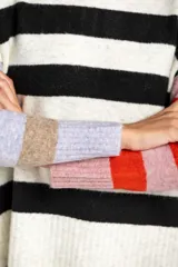 Sweater color crema con rayas horizontales en tonos rosa, marrón y verde.