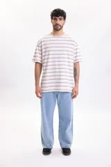 Remera oversize de manga corta con diseño de rayas horizontales en tonos beige, marrón y blanco, con cuello redondo.