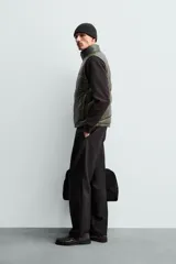 Chaleco acolchado de corte regular, confeccionado en tejido técnico repelente al agua. Presenta cuello subido, cierre frontal de cremallera, bolsillos laterales con cierre oculto y bajo ajustable con elástico. Relleno de plumón y pluma.