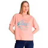 Remera de corte holgado y relajado, color rosa salmón, con cuello redondo y mangas cortas. Presenta un estampado gráfico frontal con estilo retro en tonos azul y rosa.