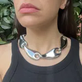 Collar corto plateado con cadena de eslabones y dijes con forma de gota.