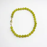 Collar de cuentas esféricas de jade limón de 10 mm, con nudos de hilo color salmón entre cada cuenta. Presenta un cierre de mosquetón metálico con baño de oro.