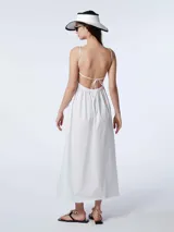 Vestido largo blanco de algodón con escote en V, breteles finos regulables y espalda descubierta con lazo para atar. Presenta un diseño holgado con bolsillos laterales.