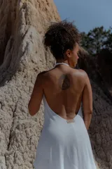 Vestido largo de color blanco, con escote en V pronunciado y tiras largas que permiten anudarlo de múltiples formas. Presenta tajo en ambos laterales y forro interno.