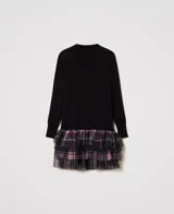 Vestido corto negro de punto liso con cuello en V y manga larga. Presenta capas de tul aplicado con estampado de cuadros multicolor.