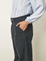 Pantalón de corte recto y tiro medio, confeccionado en tela de pana color azul piedra. Presenta cierre frontal con botón, bolsillos laterales y detalle de pinzas en la cintura.