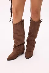 Bota de caña alta estilo western confeccionada en símil gamuza, con diseño slouchy y punta afinada.