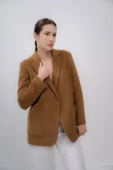 Blazer color camel de baby alpaca, con cuello de solapa, cierre frontal con botones y bolsillos laterales.