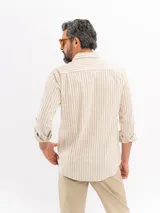Camisa de manga larga con diseño de rayas verticales en tonos beige y blanco, cuello camisero y cierre frontal con botones.