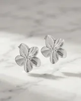 Caravanas de acero con diseño de flor de cinco pétalos con textura estriada y centro con pequeños puntos en relieve.