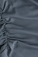 Remera gris oscuro de punto suave, con hombros caídos, mangas cortas y frunces laterales.