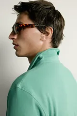 Remera polo regular fit de color gris oscuro, confeccionada en tejido de algodón con textura de rayas verticales. Cuenta con cuello solapa, cierre frontal con botones y mangas cortas con terminación en rib.