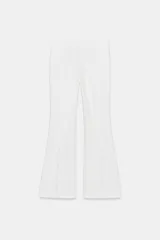 Pantalón de tiro medio color blanco, de corte flare y acabado evasé, con detalle de costura lateral y cierre frontal con cremallera oculta.