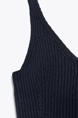 Top de punto acanalado en color azul marino, con escote en pico y tirantes. Presenta un detalle de cinturón fino al tono con un aplique metálico dorado en el centro.