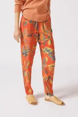 Pantalón de viscosa color naranja con estampado de hojas y lunares.