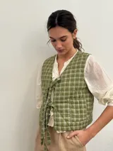 Chaleco verde claro con diseño acolchado y estampado a cuadros, sin mangas y con tiras para anudar en el frente.