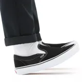 Championes Vans Skate Slip-On negros de gamuza, con elástico lateral y suela blanca de goma. Diseñados para skateboarding, con tecnología Duracap y Popcush para mayor durabilidad y amortiguación.