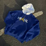 Canguro Nike Jordan de algodón, color azul con capucha blanca. Presenta el logo Jumpman en color amarillo integrado en la palabra 'BRASIL' estampada en el frente. Cuenta con bolsillo tipo canguro y puños acanalados.