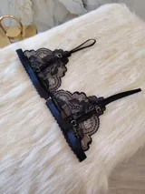 Bralette negro de encaje con diseño triangular, breteles regulables y cierre trasero con gancho.