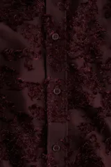 Camisa de manga larga confeccionada en tejido jacquard con textura de relieve. Presenta cuello clásico, cierre frontal con botones, puños abotonados y bajo con aberturas laterales redondeadas.