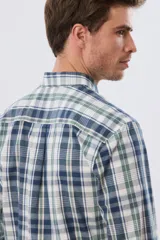Camisa de manga larga de calce slim, con diseño a cuadros en tonos azul oscuro, verde y blanco. Presenta cuello camisero con botones y bolsillo ojal en el pecho con detalle bordado.