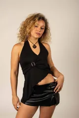 Top halter de color negro, con escote en V cruzado y detalle de hebilla metálica lateral. Presenta diseño asimétrico en el dobladillo inferior.
