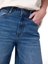 Pantalón de jean azul índigo de corte wide leg, tiro alto, diseño clásico de cinco bolsillos y cierre frontal con cremallera y botón.
