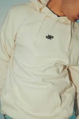 Hoodie color crema de corte oversize con capucha y logo pequeño en el pecho.