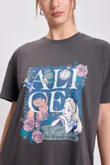 Remera oversize de manga corta, color gris oscuro con efecto gastado, con estampado frontal de Alicia en el País de las Maravillas, incluyendo el texto "ALICE In Wonderland" rodeado de flores.