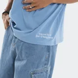 Remera negra de corte boxy con costuras a la vista en contraste de color blanco. Presenta un pequeño logo estampado en el centro del pecho y una frase bordada en el bajo lateral. Posee mangas cortas y cuello redondo.