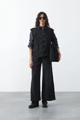 Chaleco de jean en tono celeste claro, con corte recto, cuello camisero, cierre frontal con botones metálicos y costuras visibles.