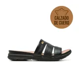 Sandalia plana de cuero color negro, con tiras anchas en el empeine, una de ellas con textura trenzada y detalle de aplique metálico dorado.