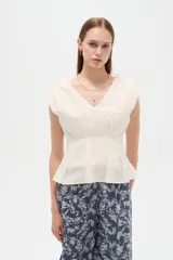 Blusa de lino color blanco, con cuello en V, pinzas de entalle y diseño al cuerpo con faldón acampanado.