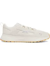 Championes Under Armour modelo Street Mirage, color beige con detalles en blanco. Presentan una parte superior de malla transpirable con superposiciones de gamuza, entresuela de EVA acolchada y suela exterior de goma dentada en color caramelo.