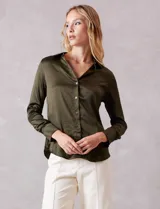 Camisa de satén color verde oliva, con cuello clásico, cierre frontal con botones metálicos y mangas largas con puños abotonados.