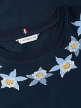 Remera de algodón Tommy Hilfiger en color azul marino, con cuello redondo y mangas cortas. Presenta un delicado diseño bordado de flores alrededor del escote y el pequeño logo de la bandera de la marca en la manga.