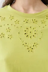 Remera de manga larga color verde lima, con escote redondo y detalle de bordados calados en forma de pico en la zona del pecho.