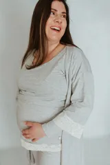 Pijama corto gris a rayas horizontales, apto para embarazo y lactancia. Incluye remera de manga corta con apertura para amamantar y short con elástico ajustable en la cintura. Detalles de puntilla elastizada en remera y short.