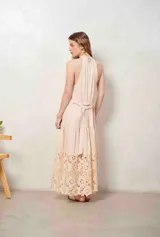 Vestido largo beige con cuello halter y detalle de broderie calado en el dobladillo inferior.