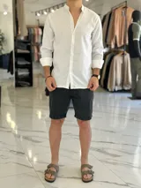 Camisa de lino color beige, de manga larga con puños arremangados y cuello mao. Cuenta con cierre frontal de botones y diseño clásico.