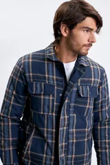 Sobrecamisa de franela a cuadros en tonos azul marino y beige, con cierre frontal de cremallera, bolsillos superiores con solapa y bolsillos laterales.