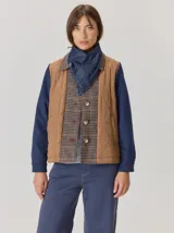 Campera de diseño híbrido con frente acolchado en color tostado, solapas y cuello en tejido de lana con patrón de cuadros tipo príncipe de gales, y mangas en paño de lana color azul marino. Cuenta con cierre frontal de botones.