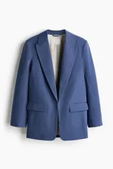 Blazer de sarga color azul, sin cierre, con solapas de pico, bolsillos delanteros con solapa y mangas largas.